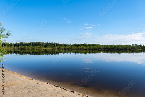 Beautiful natural landscape of a forest lake and blue sky with clouds.