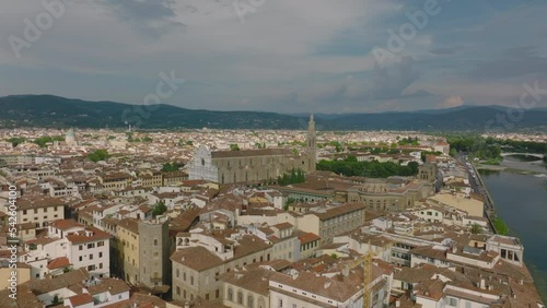 Fly above streets and houses in historic city centre. Revealing Piazza di Santa Croce with famous basilica. Florence, Italy photo