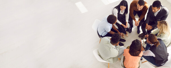Copy space banner background with coach or psychologist providing professional guidance to group of people. Business team talking while sitting in circle in room with white floor high angle from above