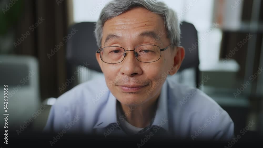 Senior asian business man working at his office. He looking into computer monitor and working with smiling.
