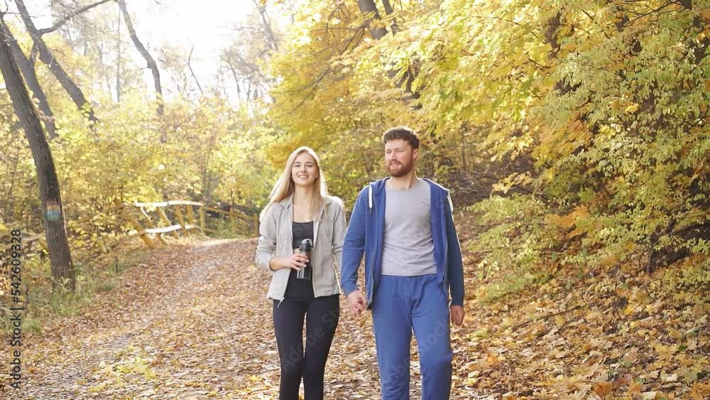 happy man and woman walking in the autumn forest after jogging in the fresh air, a young couple loves to walk in the forest in autumn happy man and woman walking in the autumn forest after jogging in the fresh air, a young couple loves to walk in the forest in autumn
