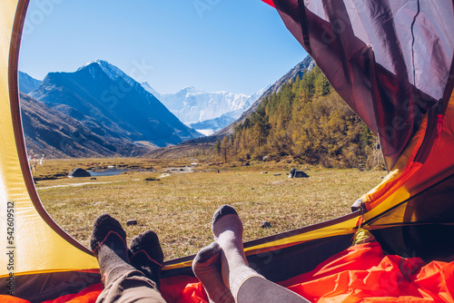 Two people lying in tent with a view of mountains. Belukha Mountain view from the tent in Akkem lake valley. Altai picturesque valley view.