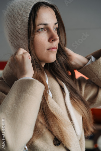 Elegant brunette woman with long hair wearing beige wool coat and cozy grey hat. Autumn trendy outdoor fashion