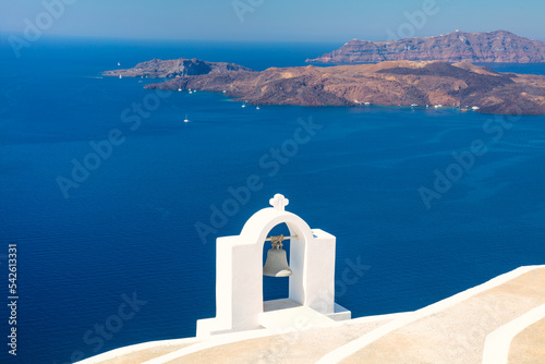 Santorini, Greece. Composition with traditional white architecture and a bell against the backdrop of the blue sea and volcanic natural islands.