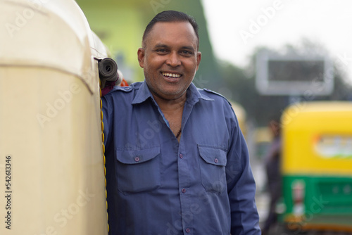 Portrait of a smiling auto rickshaw driver standing in auto stand photo