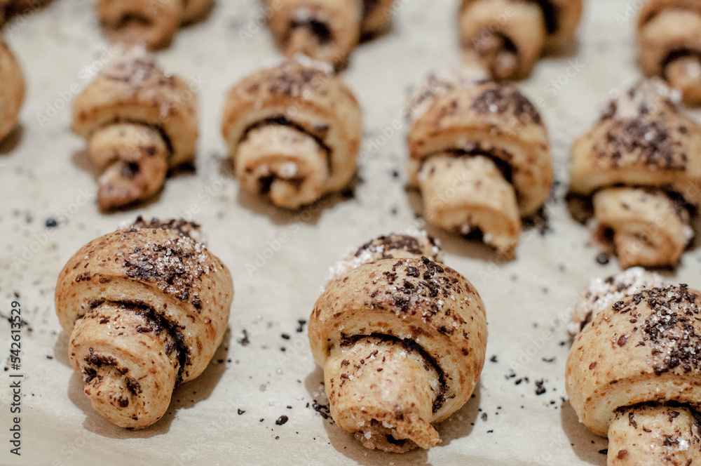 Mini croissants with chocolate crunchy curd of dough on baking paper.