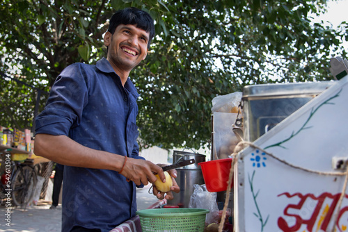 Portrait of a smiling male vendor peeling off potato photo