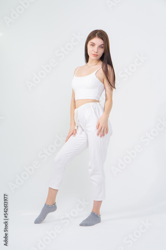 Young beautiful brown-haired girl in a white top and trousers posing on a white background © Михаил Таратонов