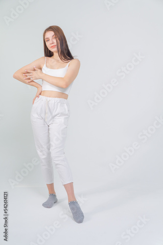 Young beautiful brown-haired girl in a white top and trousers posing on a white background © Михаил Таратонов