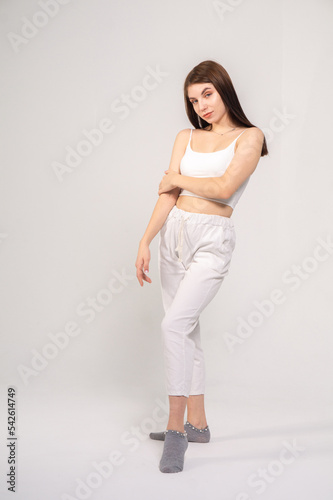 Young beautiful brown-haired girl in a white top and trousers posing on a white background © Михаил Таратонов