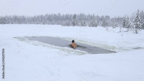 Siberia. Winter swimming. A man swim in the ice hole of a frozen lake.