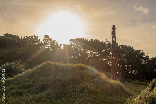 Sunset rays shine over a tall pouwhenua