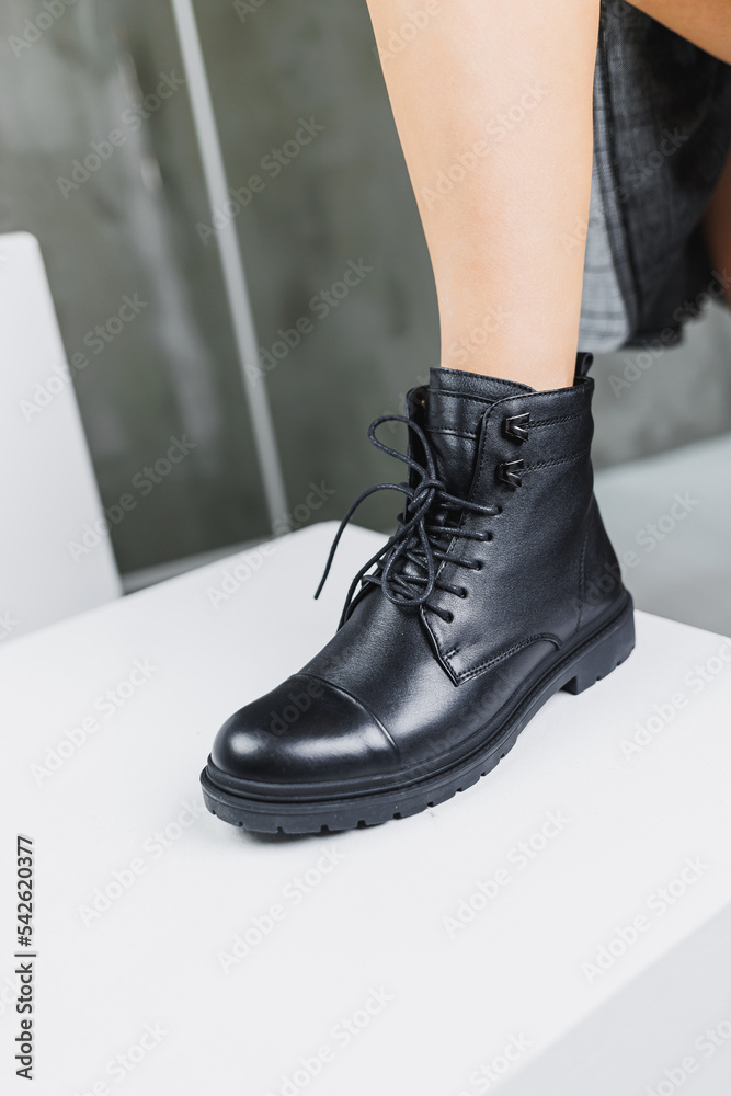 Slender female legs in black winter leather boots. Fashionable women's boots. Women's leather shoes.