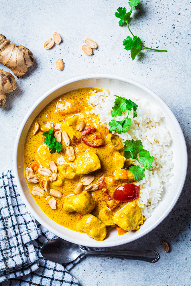 Thai chicken and peanut curry with rice in white bowl, gray background. Asian cuisine concept. - obrazy, fototapety, plakaty 