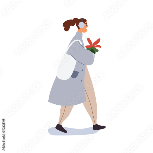 Happy woman walking with Christmas poinsettia plant outdoors. Girl going with...