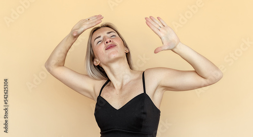 Cheerful caucasian young woman grimacing, fooling and dance around on beige background. Humor concept
