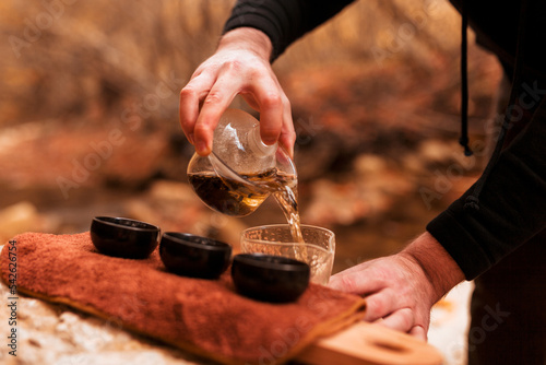 hand pours Chinese gaba tea into cups against the backdrop of an autumn landscape