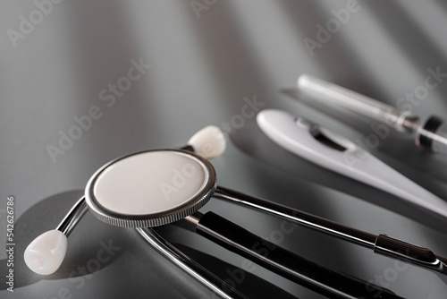 Doctor's tools for check up: stethoscope, thermometer and syringe on gray background