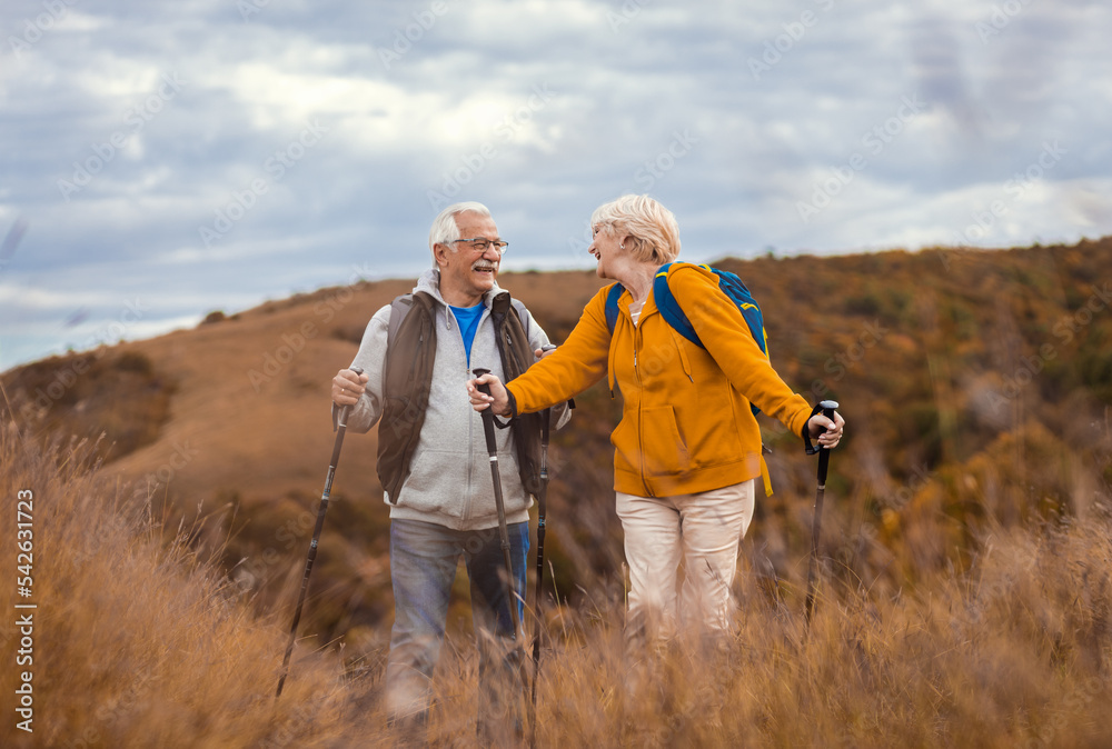 Active senior couple with backpacks hiking together in nature on autumn day. Active senior couple with backpacks hiking together in nature on autumn day.