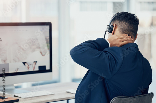 Neck pain, call center worker and tired employee man working in office chair the desk of online telemarketing sales business. CRM consultant, workplace injury and pinched nerve from company computer