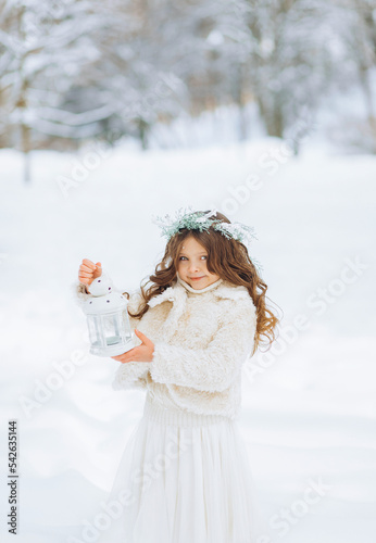 Childhood, portrait of happy little girl in winter clothes with lantern outdoors in the park