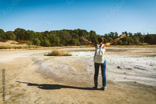 Young woman trekking to the Solfatara di Manziana (sulphurous area) in Italy. The woman opens her arms as a sense of freedom. photo