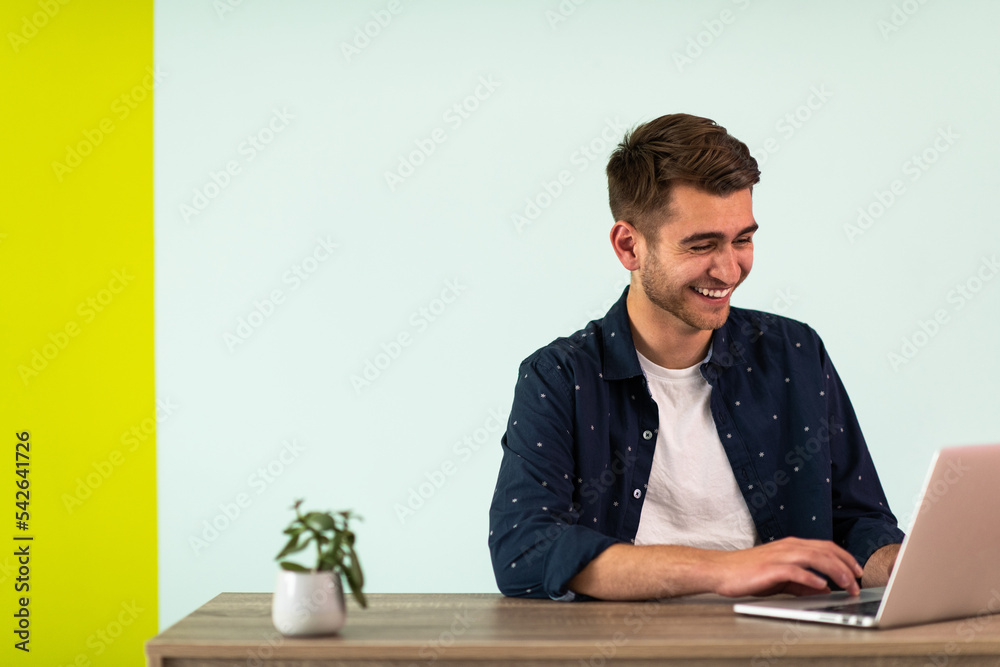 Smiling young man freelancer using laptop studying online working from home Smiling young man freelancer using laptop studying online working from home