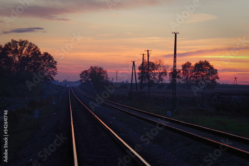 Kolorowe niebo po zachodzie słońca nad torami kolejowymi.