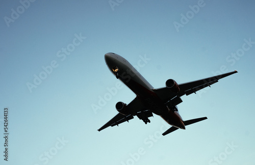 The silhouette of a passenger plane coming in for landing against the backdrop of the sunset sky.