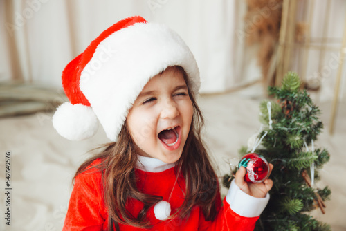 A little girl on the beach wearing a Santa Claus hat and . The child is resting on the sea. The concept of Christmas holidays at sea. A place to copy.