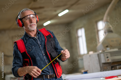 Man in ear protectors and measuring tape in hands