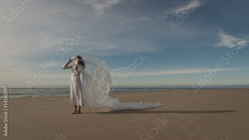 abstract art portrait of woman in white wedding dress on beach dancing covered by plastic foil