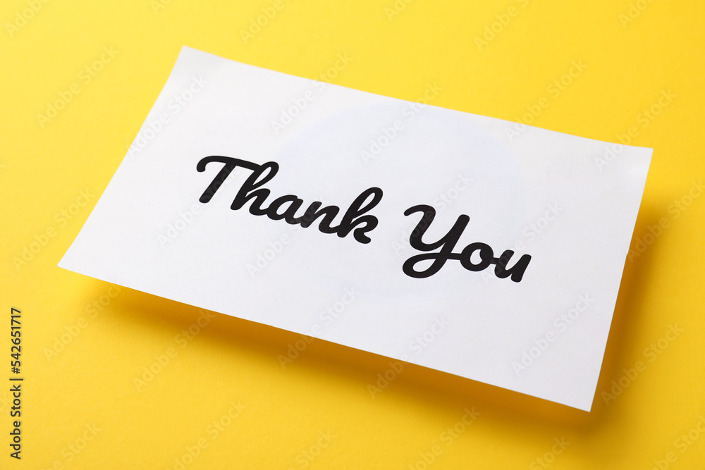 White paper note with phrase Thank You on yellow background White paper note with phrase Thank You on yellow background