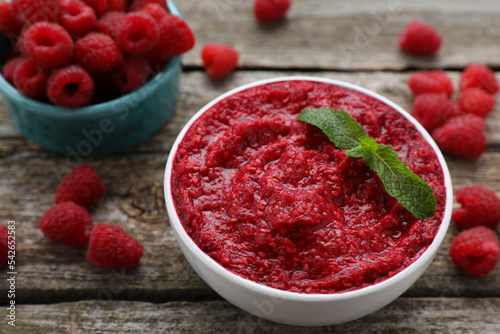 Fotomural Raspberry puree in bowl and fresh berries on wooden table, closeup