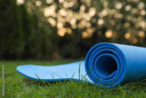 Blue karemat or fitness mat on green grass outdoors