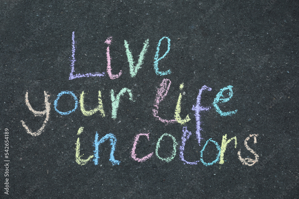 Fototapeta premium Phrase Live Your Life In Colors written on asphalt, top view