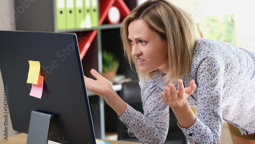 Upset woman looking at laptop screen with angry expression
