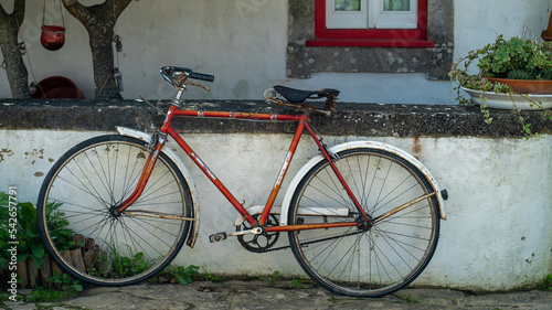 bicicleta vermelha encostada a um muro de uma casa antiga photo
