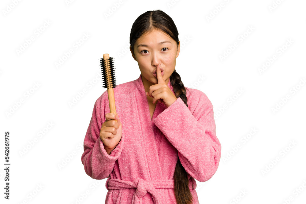 Young asian woman holding an hair comb isolated keeping a secret or asking for silence. Young asian woman holding an hair comb isolated keeping a secret or asking for silence.