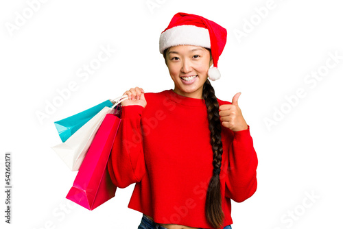 Young asian woman shopping a christmas presents isolated Young asian woman shopping a christmas presents isolated smiling and raising thumb up