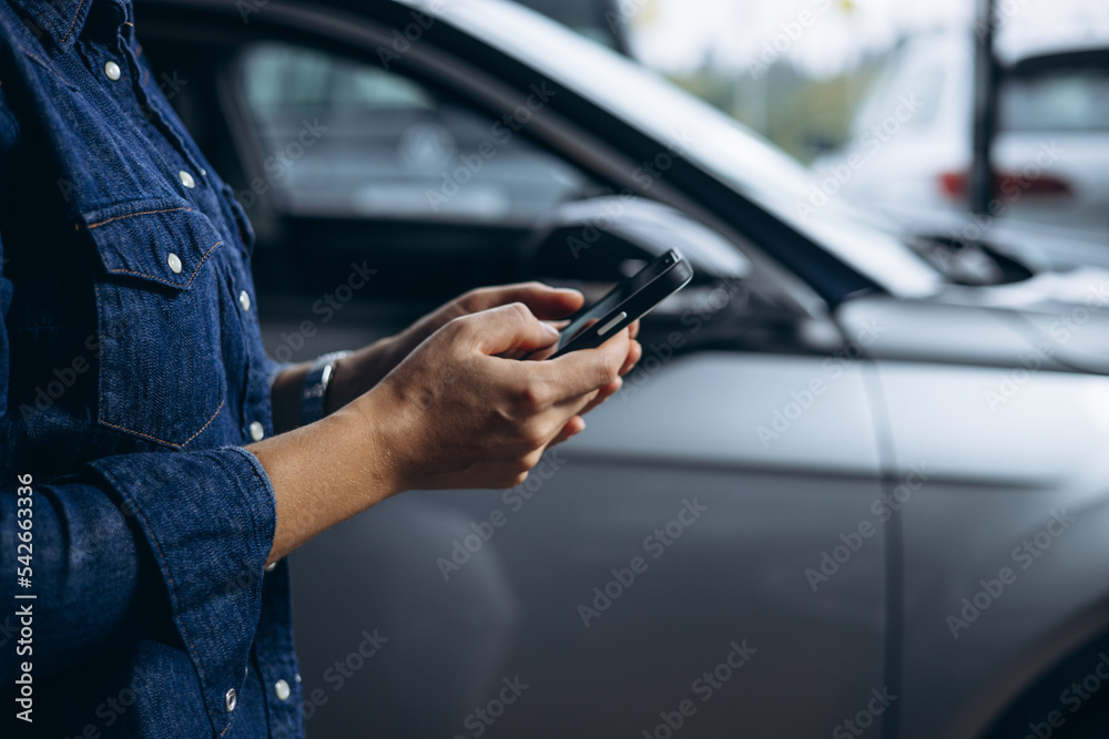 Woman standing by the car and using phone