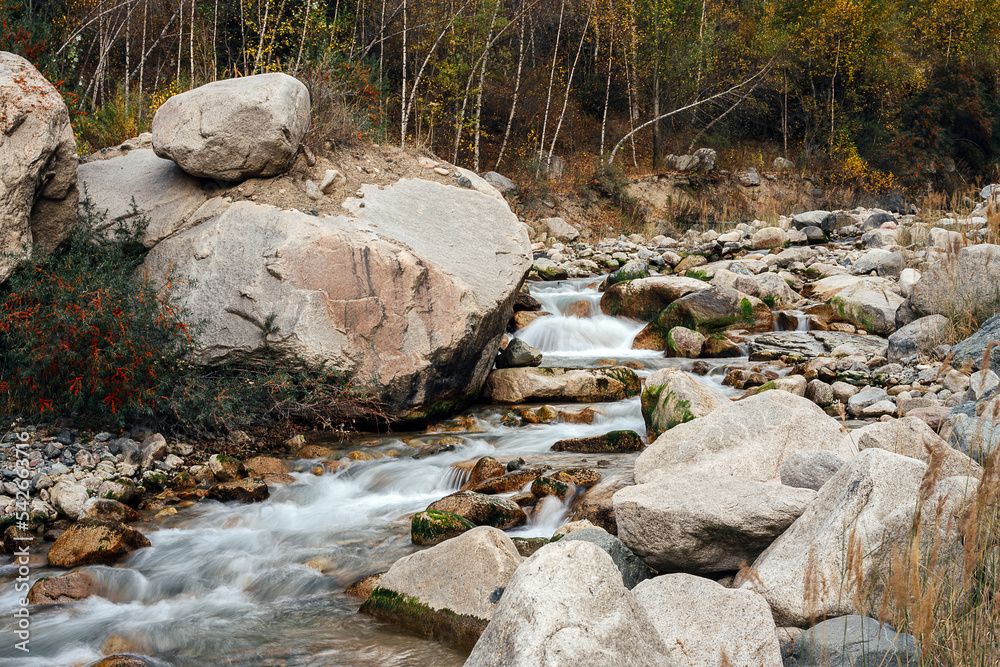Mountain water stream with stony banks and some forrest in background. Mountain water stream with stony banks and some forrest in background.