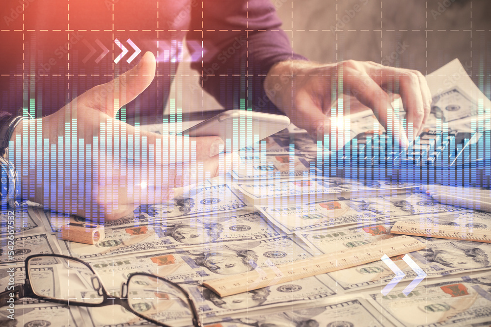Double exposure of man's hands holding and using a digital device and forex graph drawing. Financial market concept.