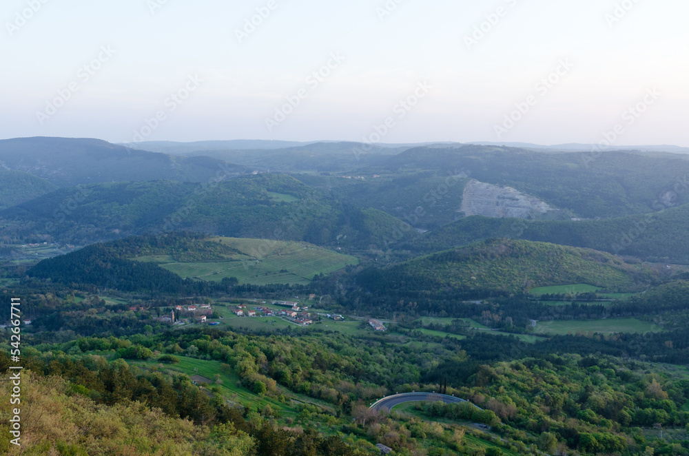 Scenic view to beautiful green hills and big bridge against red orange sky in spring from Črni Kal, Slovenia
