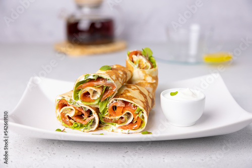 Pancakes with salmon (trout), sour cream, greenstuff and tea. Thin, not sweet blinchiki stuffed with red fish. Traditional Russian and Ukrainian dish. Feast of Maslenitsa. Selective focus, close-up. photo