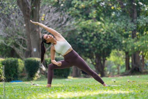 Asian slim woman exercise alone in the park,Tired from workout, Play yoga concept.