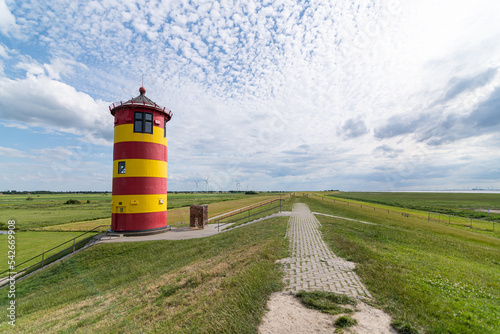 Pilsumer Leuchtturm auf dem deich mit gr  ner wiese und blauem bew  lktem himmel