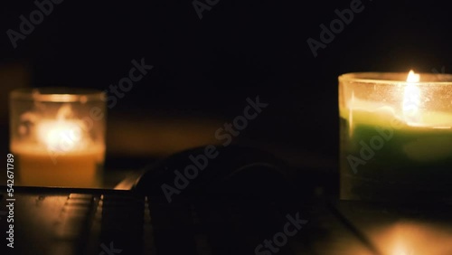 Burning candles, laptop and cellphone on the table. Candles in dark room. No electricity in the house. Power outage in the city. Blackout, energy crisis concept. 