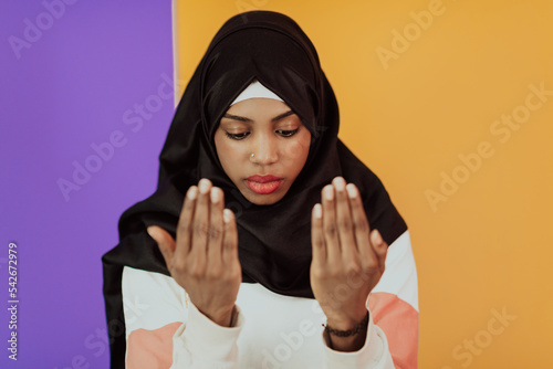 African muslim woman wearing hijab and traditional muslim clothes posing in front of yellow background © .shock