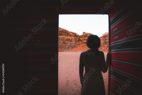 Tableau sur toile Woman person stand in desert bedouin camp inside traditional tent with open door